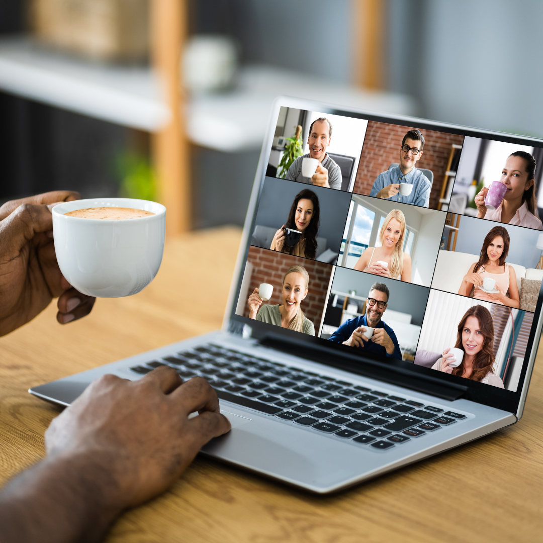 A photograph of a person holding a coffee cup while speaking with people in a group video call.
