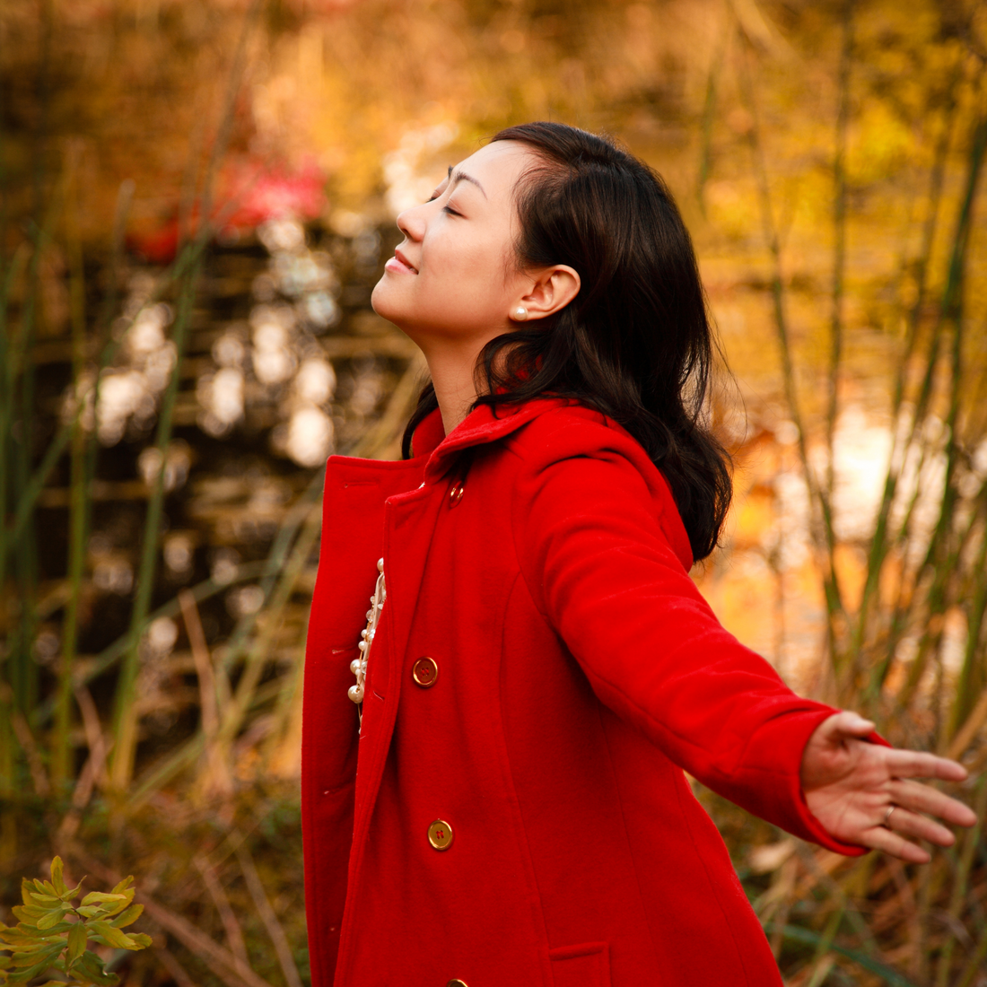 woman wearing a red jacket with her arms spread wide open.