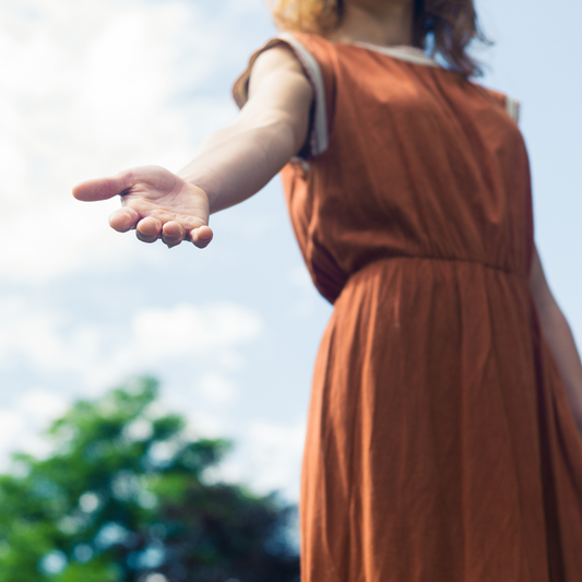 A photograph of a woman wearing a red dress holding out her hand to support someone.
